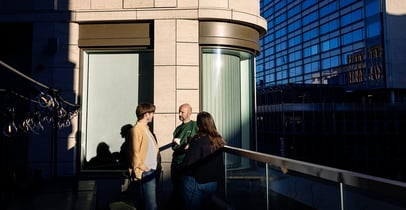 Ihmisiä seisomassa ja keskustelemassa rakennuksen ulkopuolella